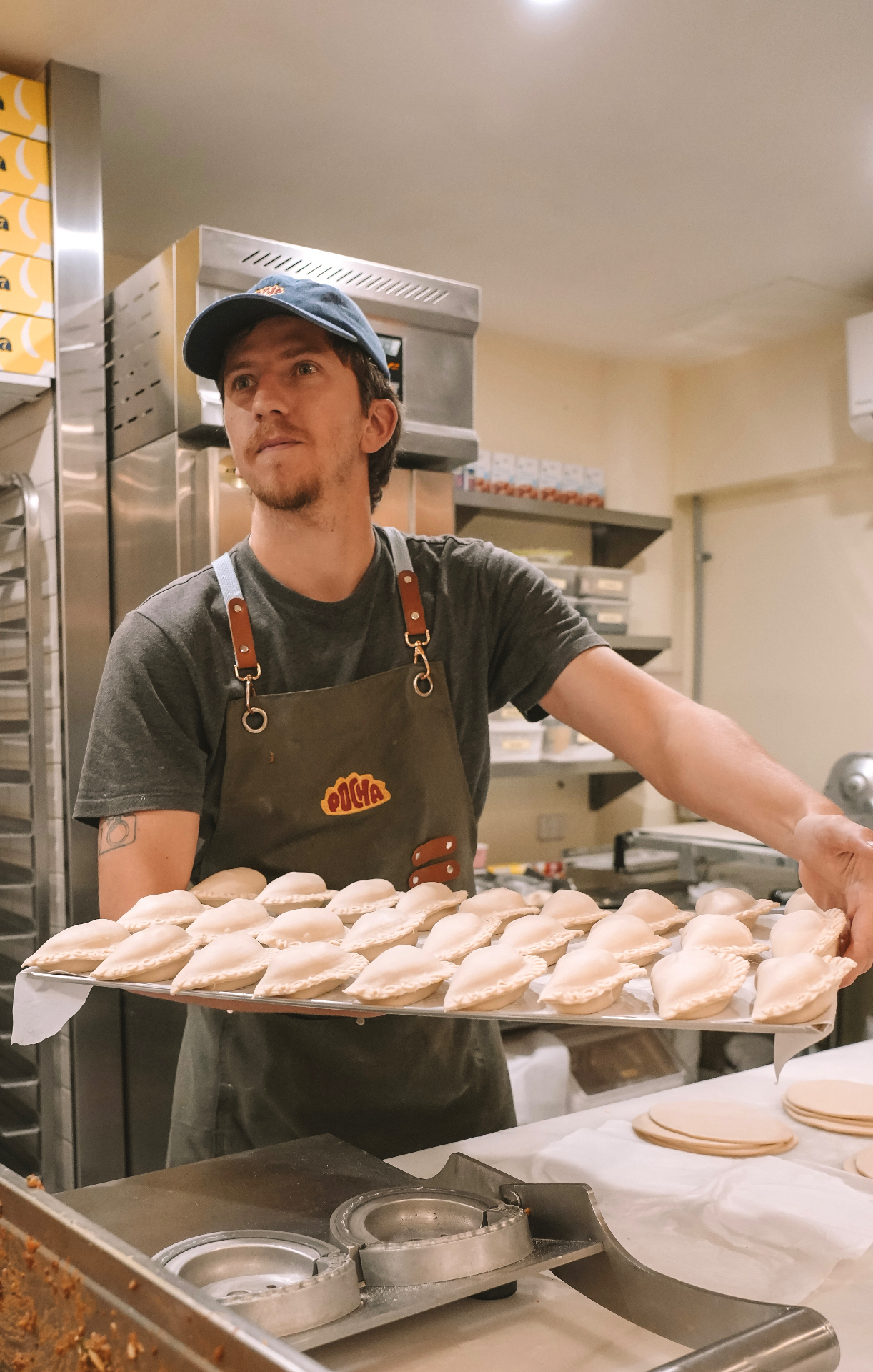 Mariano holding a fresh tray of empanadas in the Pocha kitchen