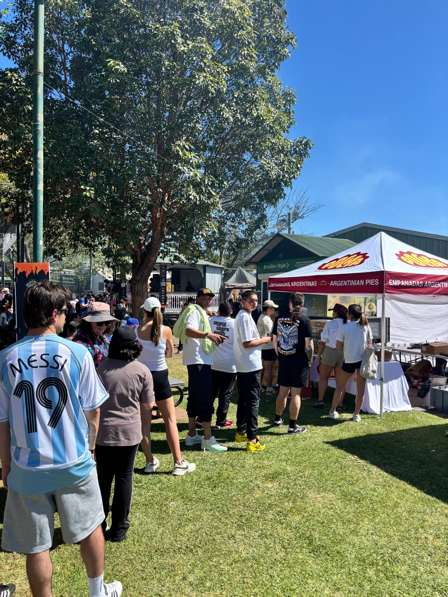 Customers gathering at the Pocha Empanadas market stall on a sunny day